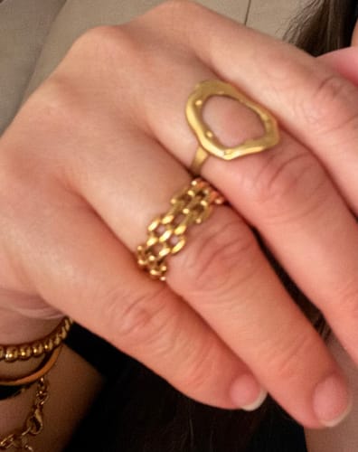 Reviewer's hand wearing the wide, gold Malibu Ring stacked with another ring.