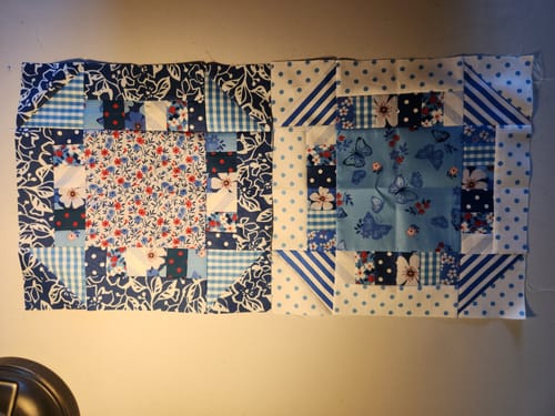Reviewer shows two completed quilt blocks made with patterned blue and white fabric from their Mrs Quilty Subscription Box.