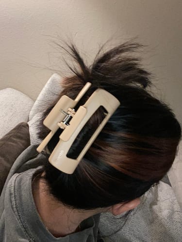 Customer resting with their dark hair held up by a light-colored cloud clip.