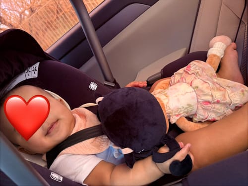 A reviewer's baby in a car seat with the Personalized Princess Petal doll lying next to them.