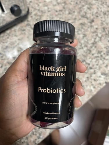 Customer holding a bottle of black girl vitamins Probiotics, showing the dark gummies inside.