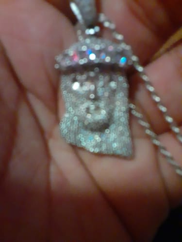 Close-up: A blurry photo of a reviewer holding the sparkling Moissanite Deluxe Jesus Pendant in their hand.