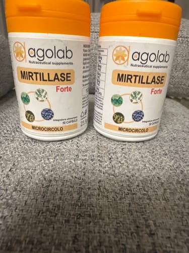 Recensore mostra due flaconi dell'integratore Mirtillase Forte su un divano.