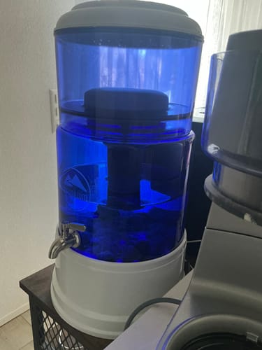 Kundenfoto des montierten MAUNAWAI PI®PRIME Wasserfilters mit blauem Tank und weißem Sockel.
