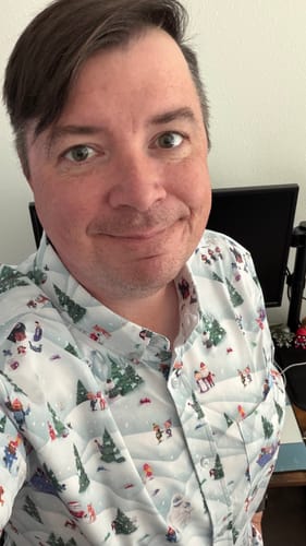 Customer smiling while wearing the festive Rudolph 'Stop Motion Wonderland' short sleeve shirt.