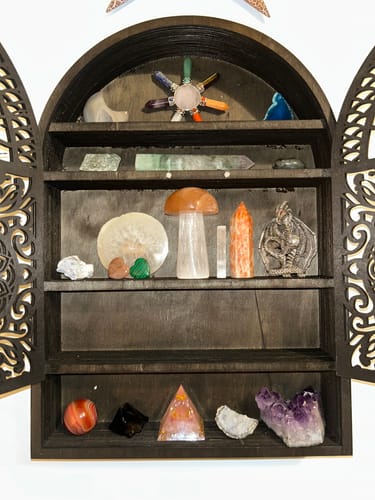 Customer's collection of AuraBloom Subscription Box crystals displayed on dark wooden shelves.