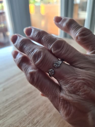 A customer's hand wearing a silver-colored open ring with two paw print designs.