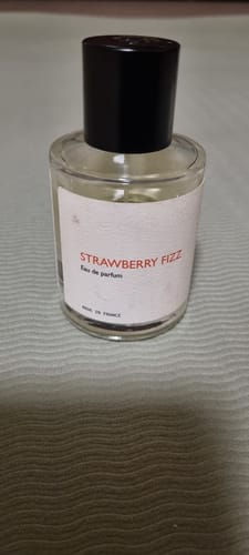 Customer's Strawberry Fizz perfume in a glass bottle with a white label and black cap.