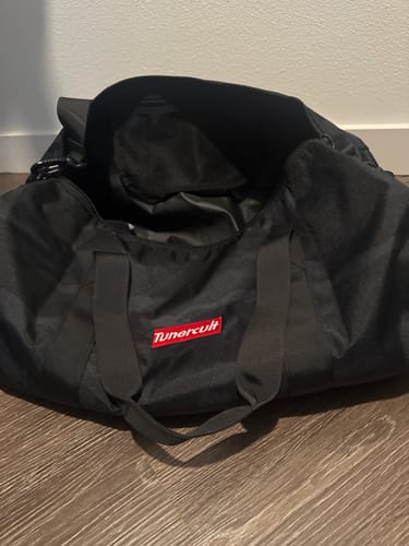 Reviewer's black duffle bag is open on the floor with its red logo visible.