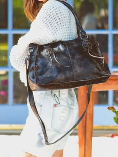 Customer carrying the black distressed leather Rockababy BedStu Purse on their shoulder with a crossbody strap attached.
