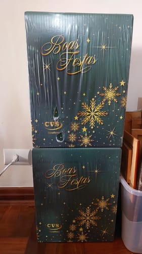 Avaliador mostra as duas caixas da Cesta de Natal Cristal, uma empilhada sobre a outra.
