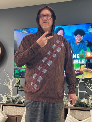 Reviewer posing in the 'The Chewie' Performance Hoodie with the hood up and making a peace sign.