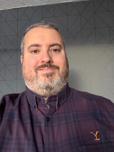 Customer in a close-up wearing the dark purple plaid Yellowstone Long Sleeve Flannel with the 'Y' logo on the chest.