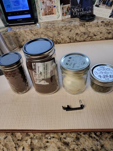 Customer's four mason jars with different lids, sealed on a kitchen counter to show the results of the Mason Genie Vacuum Sealer Kit.