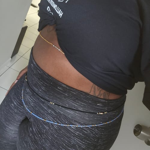 A customer wearing multiple colorful strands of Nubian Jewel Waist Beads around their waist and hips.