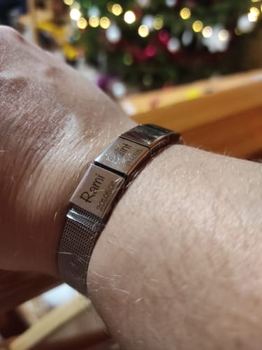 Customer showing a close-up of their personalized Lux bracelet with two engraved name pendants.