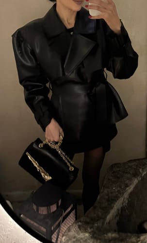 Reviewer in a mirror selfie wearing the elegant black Vegan Leather Cropped Trench Jacket, belted at the waist.