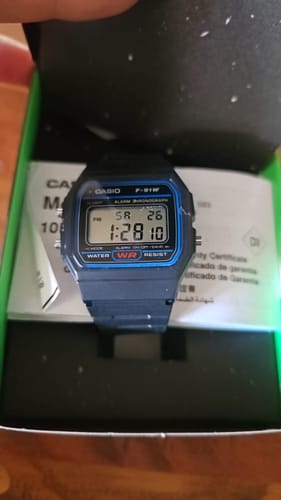 Un cliente muestra su reloj Casio Vintage F-91W-1DG nuevo dentro de su caja de empaque.