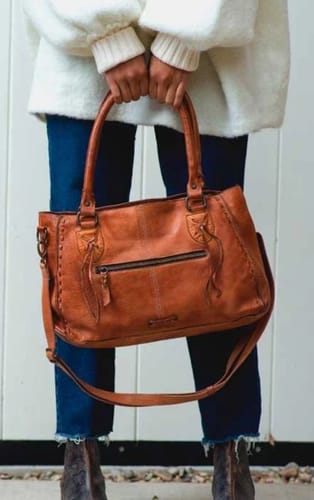 Customer holding the brown leather Rockababy BedStu Purse by its top handles.