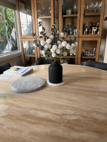 Customer's Faux Arrangement with white flowers and green stems displayed in a black vase on a dining table.