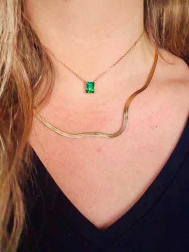Customer wearing the gold Essentials Snake Chain Necklace layered below a shorter necklace with a green pendant.