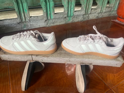Reviewer's pair of light pink adidas Breaknet Sleek shoes with white stripes and a gum sole, displayed on a wooden plank.