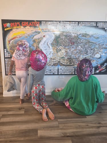 Customer's children interacting with the large World's Greatest Search & Discover poster mounted on a wall.