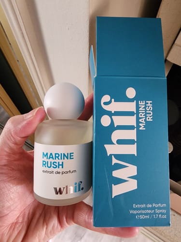 Customer holding the frosted Marine Rush cologne bottle next to its blue box.