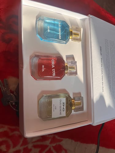 Reviewer's OUD Supreme BUNDLE showing three colorful perfume bottles sitting inside the open product box.