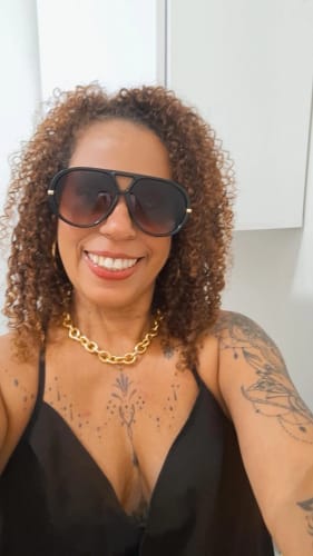 Cliente sorrindo ao usar os Óculos Veneza oversized.