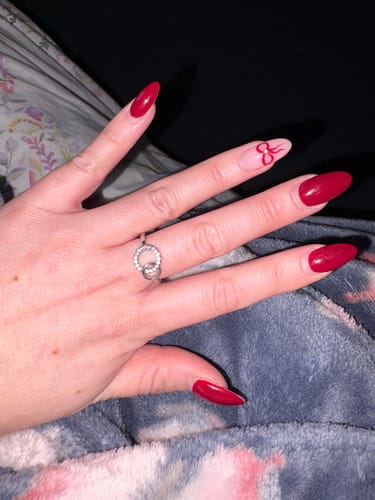 Customer's hand with a red manicure, wearing the To My Sister - Forever Linked Ring.