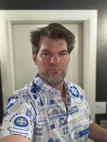 Reviewer taking a selfie in the 'R2 Deconstructed' shirt, featuring its blue and white schematic pattern.