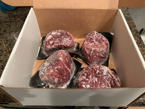 Reviewer's box containing four individually vacuum-sealed and marbled USDA Prime Filet Mignon Steaks.