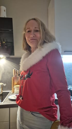 Kunde som har på seg den røde juletrykk-toppen med en myk, hvit pelskant rundt halsen.