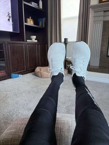 Reviewer relaxing with their feet up, wearing the white MUUV Flow Wide Toe Box Pickleball Shoes.