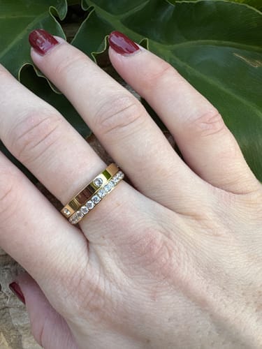 Customer's hand showing the gold Eternity Band Ring stacked with another ring on their middle finger.