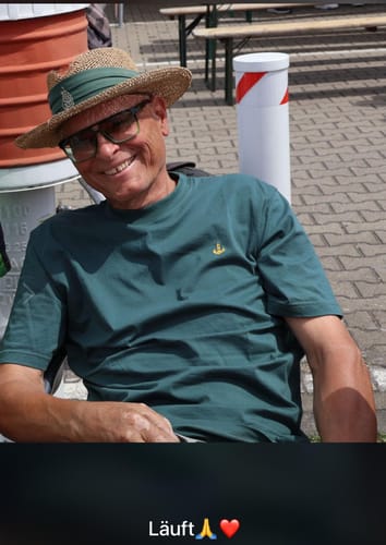 Ein lächelnder Kunde trägt das grüne Mooinzen Signature Bio T-Shirt im Freien.