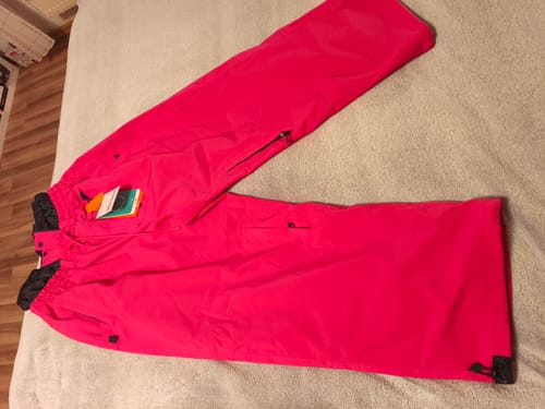 Customer's new pink baggy Snow Pants laid out flat on a bed, showing a zippered thigh vent.