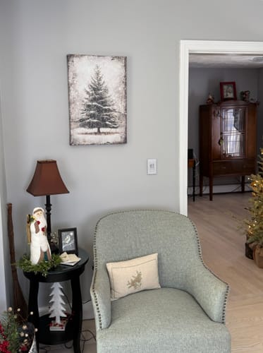 Customer's Vintage Pine Tree Christmas Wall Art hanging on a light gray wall above an armchair in a festive room.