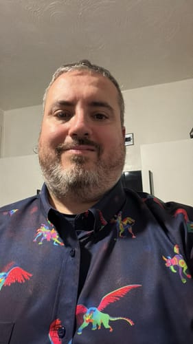 Reviewer in a close-up photo wearing the colorful Coco "Dante y Pepita" short sleeve shirt.