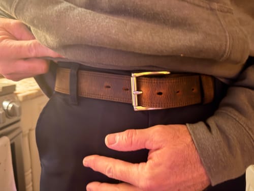 Close-up of a reviewer wearing the brown, textured Wyoming Bison belt with dark pants.