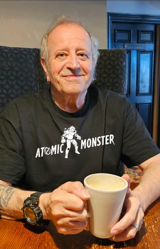 Reviewer wearing the black unisex t-shirt with the 'Atomic Monster' front graphic while holding a mug.