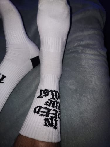 Customer wearing the white SPEED CREW SOCKS, showing the black 'IN SPEED WE TRUST' text along the calf.