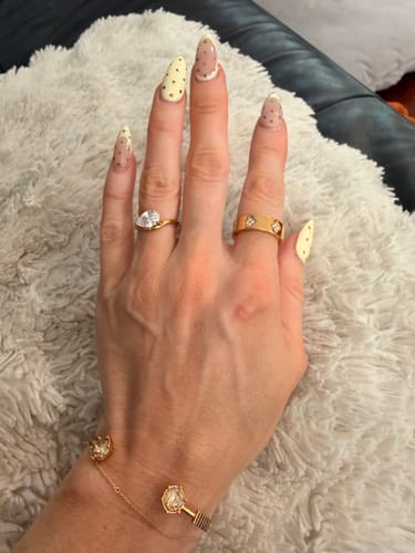 Customer's hand wearing the gold Pia Ring, showing its pear-cut stone and distinct wave band.
