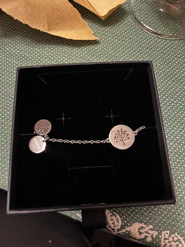 Customer's silver Family Tree bracelet in its black gift box, showing the engraved tree pendant and two smaller charms.