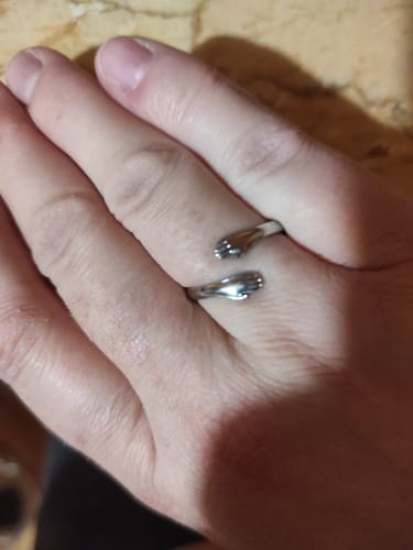 Customer's hand wearing the Mystery Gift they received: a silver-colored ring with a hugging hands design.