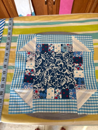 Customer's finished quilt block made from the Early Christmas Pattern, showing blue and white patchwork fabrics on an ironing board.