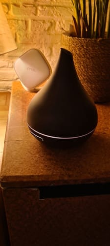 Recensent toont de donkerhouten Unity Aroma Diffuser op een houten meubel in een sfeervol verlichte kamer.