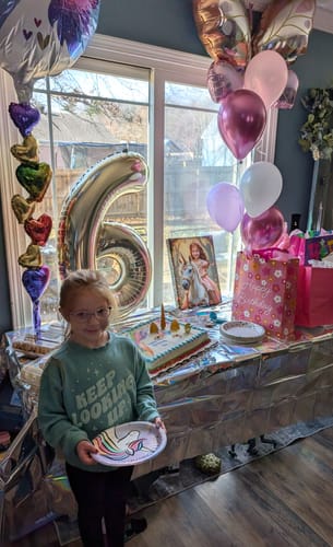 Customer's 'The Enchanted Unicorn Princess' picture displayed on a table at a child's unicorn-themed birthday party.