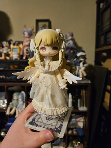 Customer holding the blonde Mystic Realm Pilgrimage action figure, an angelic doll with wings, in their hand.